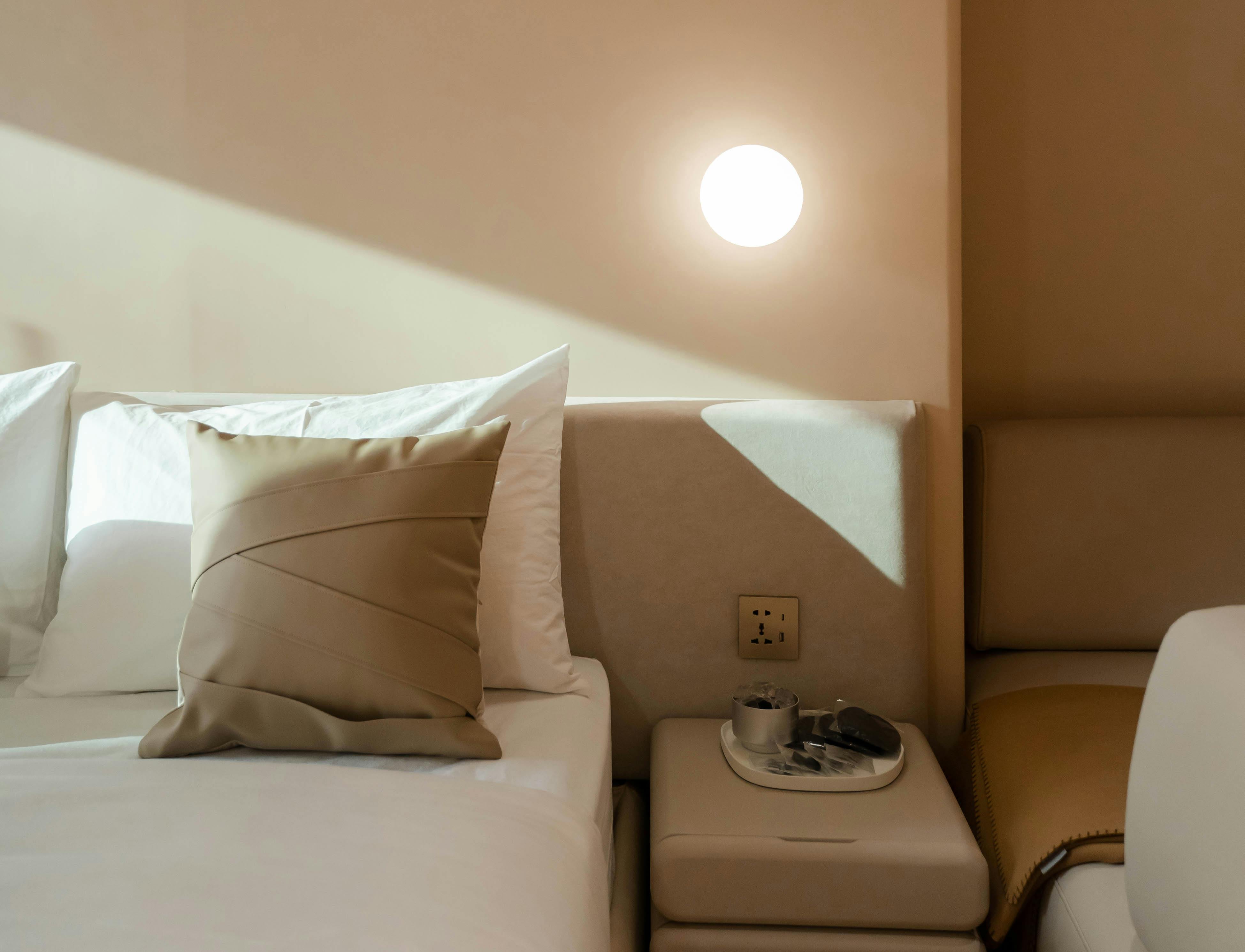 Room detail — linen pillows, warm sconce, afternoon light